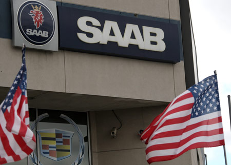 National flags of the United States flutter in front of the logo of Saab at a car dealership in New York, the United States, April 7, 2009. Saab Automobile, the troubled Swedish unit of Genral Motors Corp, has been contacted by 20 potetial buyers, with a sale planned in June, the carmaker