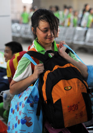 Meng Dan, a student of Sangping Middle School of Wenchuan County, southwest China&apos;s Sichuan Province, carries four bags on her shoulder at the waiting room of the Guangzhou Railway Station in Guangzhou, capital of south China&apos;s Guangdong Province, on June 17, 2009.