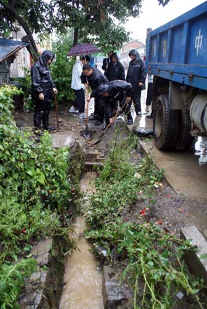 People dig a drain in rain in Ningqiang County of northwest China&apos;s Shaanxi Province, on June 19, 2009. Heavy rain has been striking some cities and counties in Shaanxi Province since June 18.