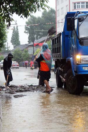 People move rubbish to drain rainwater in Ningqiang County of northwest China&apos;s Shaanxi Province, on June 19, 2009. Heavy rain has been striking some cities and counties in Shaanxi Province since June 18. 