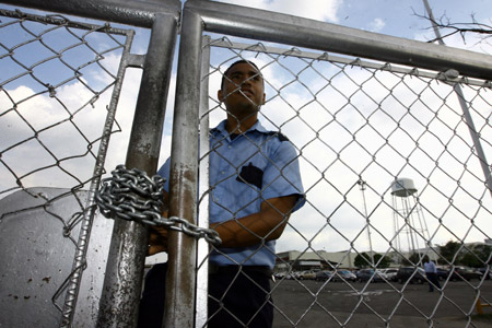 A guard locks the entrance door of a General Motor (GM) assembly plant in Valencia, Venezuela, on June 19, 2009. The assembly plant was temporarily shut down for 3 months because it cannot import car parts timely.