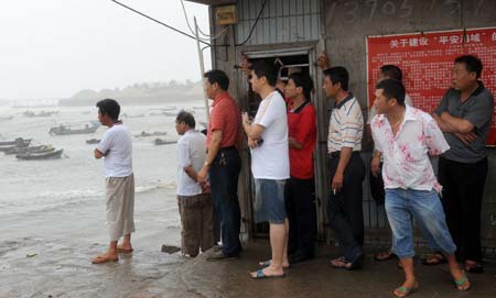 People watch their fishing boats as they brace for the upcoming Linfa, the third tropical storm this year, at a port in Jinjiang, a city in southeast China's Fujian Province, on June 21, 2009. Linfa has upgraded to strong tropical storm on June 20, and an emergency alarm was issued by the provincial weather bureau.