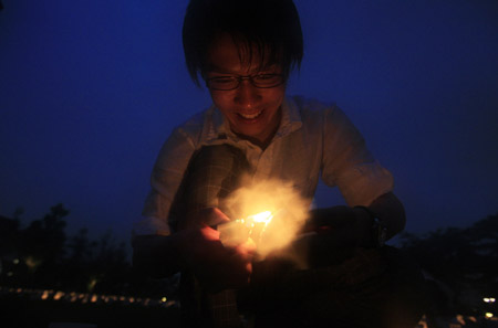 A man lightens a candle to put it into a plastic cup during the Candle Night campaign to call for saving the electricity with the lights off in Roppongi in Tokyo, capital of Japan, on June 21, 2009.