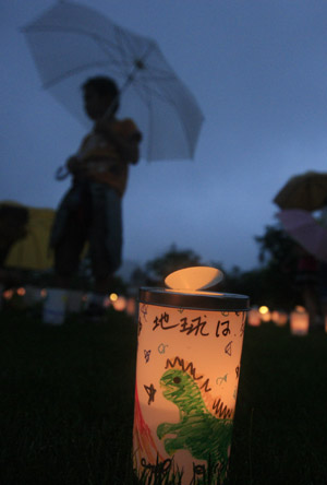 A boy passes by a plastic cup with a candle in during the Candle Night campaign to call for saving the electricity with the lights off in Roppongi in Tokyo, capital of Japan, on June 21, 2009. 
