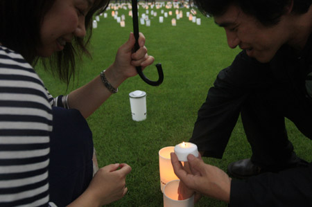 A couple lighten a candle to put it into a plastic cup during the Candle Night campaign to call for saving the electricity with the lights off in Roppongi in Tokyo, capital of Japan, on June 21, 2009. 