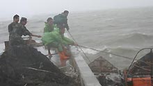 Soldiers and fishermen strive to fasten a fishing boat amid stormy weather in Zhangzhou, east China's Fujian Province on Sunday, June 21, 2009. The provincial meteorological bureau issued an orange alert for torrential rains on Monday, after tropical storm Linfa arrived on Sunday.
