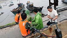 People tighten mooring fishing boats to brace for the upcoming Linfa, the third tropical storm this year, at a port in Jinjiang, a city in southeast China's Fujian Province, Sunday, on June 21, 2009. Linfa has upgraded to strong tropical storm on June 20, and an emergency alarm was issued by the provincial weather bureau.