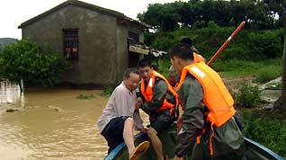 Soldiers of the local frontier defence troop rescue trapped resident in Zhao'an County, southeast China's Fujian Province, on June 22, 2009. Affected by tropical storm Linfa, the third this year, heavy rainstorm hit Zhao'an county on Sunday night. Over 100 residents trapped by floods have all been transferred to safe areas by Monday afternoon.