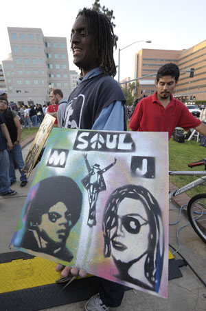 A fan holds a poster with a picture of Michael Jackson while mourning the American pop icon in Los Angeles, the United States, on June 25, 2009. Michael Jackson, the 50-year-old former 'King of Pop', was announced dead here Thursday at a hospital after suffering a heart attack at his rented home in a wealthy Los Angeles suburb.