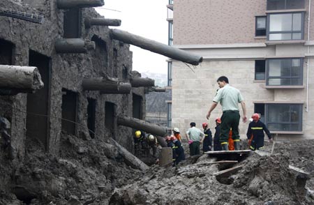 Fire fighters work at the scene of a toppled building in Shanghai, China, on June 27, 2009. A 13-storey building under construction in the 'lotus riverside' neighborhood of Minhang district fell down entirely early Saturday morning. The accident killed one person. The cause of the accident is under investigation.