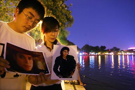 Two Chinese fans hold pictures of Michael Jackson as they attend a night gathering to mourn for the late US megastar Michael Jackson, in Beijing, China, on June 26, 2009. 