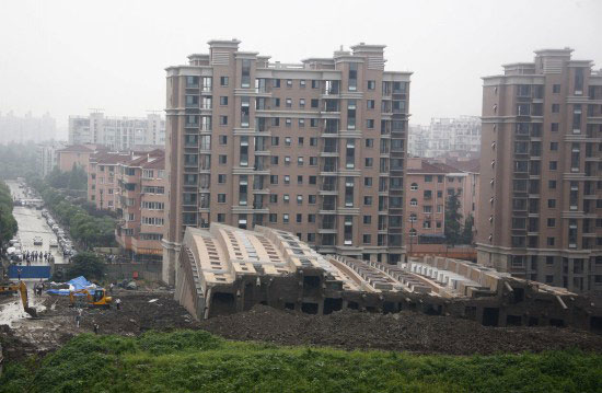 Photo taken on June 27, 2009 shows the scene of a toppled building in Shanghai, China. A 13-storey building under construction in the 'lotus riverside' neighborhood of Minhang district fell down entirely early Saturday morning. The accident killed one person. The cause of the accident is under investigation. 