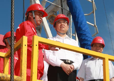 Chinese President Hu Jintao (2nd R) talks with a worker during his visit to Daqing Oilfield in northeast China's Heilongjiang Province. 