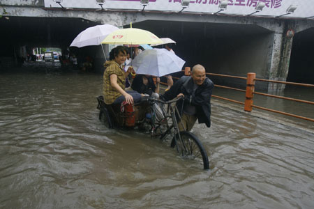 A Chinese man carries local residents with a tricycle in deep rainwater on a flooded street in Wuhan, capital city of central China's Hubei Province, on June 30, 2009. The city has been hit by seasonal summer rainfalls for days.