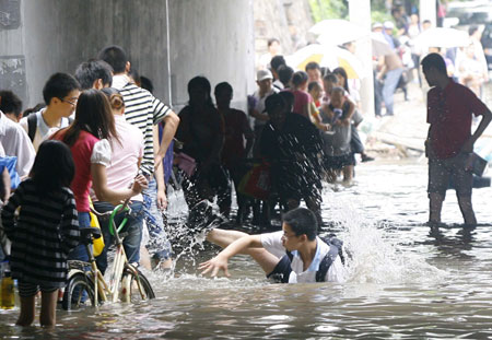 One of the local residents falls over in deep rainwater as they paddle on a flooded street in Wuhan, capital city of central China&apos;s Hubei Province, on June 30, 2009. The city has been hit by seasonal summer rainfalls for days.