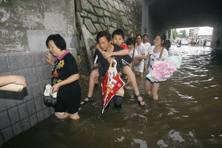 Local residents paddle in deep rainwater on a flooded street in Wuhan, capital city of central China&apos;s Hubei Province, on June 30, 2009. The city has been hit by seasonal summer rainfalls for days.