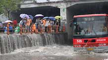 Local people look on as a city bus drives in deep rainwater on a flooded street in Wuhan, capital city of central China's Hubei Province, on June 30, 2009. The city has been hit by seasonal summer rainfalls for days.