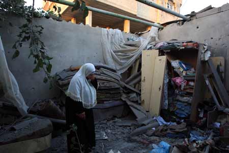 A Palestinian woman inspects her damaged house after an Israeli attack in central Gaza strip on July 2, 2009. Israel shelled the Hamas-controlled Gaza on Thursday, killing a Palestinian teenage girl, hospital workers said. An Israeli military spokeswoman said there had been clashes between soldiers and Palestinian militants near a border crossing in the area. 