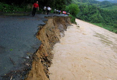 The road is eroded by the floods in Sanjiang County in southwest China's Guangxi Zhuang Autonomous Region, on July 2, 2009. A heavy storm hit Gaoji Village, Heping Village, Danzhou Village etc. in Sanjiang County from Wednesday night to Thursday morning, which caused floods in these areas. The rescuing work was undergoing.