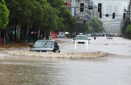 Vehicles move on the water-logging road in Pingxiang City, southeast China's Jiangxi Province, on July 2, 2009. A heavy rain hit Pingxiang City from Wednesday night to Thursday morning. The city faced frequent thunder storm recently. 