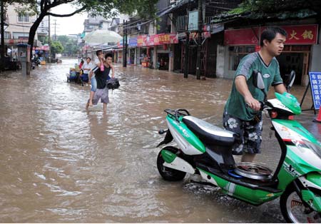  People walk on a flooded street in Guilin, a city of southwest China's Guangxi Zhuang Autonomous Region, July 3, 2009. Due to heavy rainfall, the water level of Lijiang River which passes Guilin reached 147.5 meters at 17:00 pm on Friday, 1.8 meters over the alert level. Some scenic spots in Guilin City has been closed. (Xinhua/Chen Ruihua)