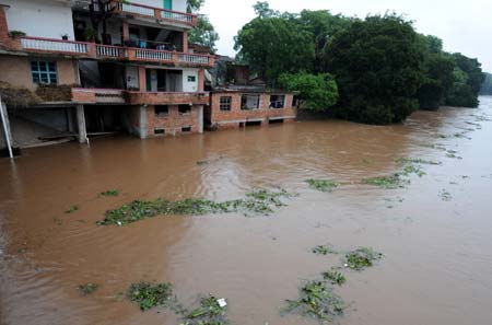 Flood submerges houses at the Xinyuan village in Ruijin, a city of east China's Jiangxi Province, July 3, 2009. More than 60,000 people have been transfered due to the flood caused by heavy rainfall in south Jiangxi Province. (Xinhua/Song Zhenping) 