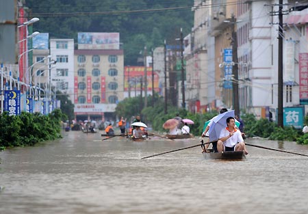 Local people paddle boats on a flooded street in Rongshui Yao Autonomous County, southwest China's Guangxi Zhuang Autonomous Region, on July 4, 2009. Floods caused by rainstorms since early the week have left four people missing and 11,845 others displaced in Guangxi.