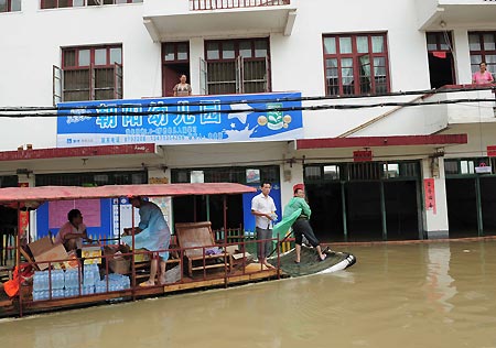 Local officials deliver food to trapped residents in Xingping Town of Yangshuo County, southwest China's Guangxi Zhuang Autonomous Region, on July 4, 2009. Floods caused by rainstorms since early the week have left four people missing and 11,845 others displaced in Guangxi. The torrential rains have also damaged 12,440 hectares of crops and killed 53,300 heads of cattle. 