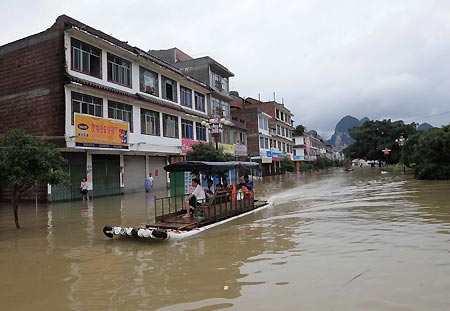 Local people evacuate by raft in Xingping Town of Yangshuo County, southwest China's Guangxi Zhuang Autonomous Region, on July 4, 2009. Floods caused by rainstorms since early the week have left four people missing and 11,845 others displaced in Guangxi. The torrential rains have also damaged 12,440 hectares of crops and killed 53,300 heads of cattle. 