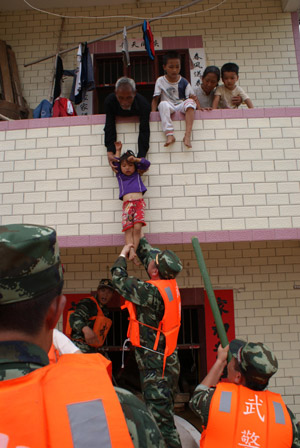 Policemen help local people to evacute in Xincheng Township of Dayu County, east China's Jiangxi Province, on July 4, 2009. Rainstorms have swept Jiangxi since Tuesday, leaving two people dead, one missing and over 3.9 million others affected. 