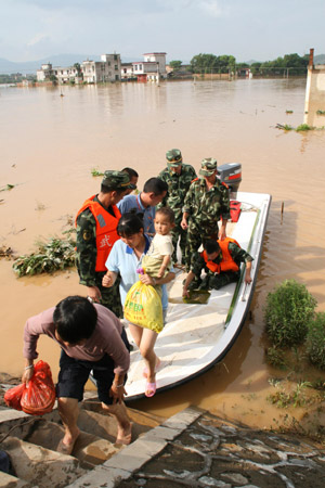 Policemen help local people to evacute in Xincheng Township of Dayu County, east China's Jiangxi Province, on July 4, 2009. Rainstorms have swept Jiangxi since Tuesday, leaving two people dead, one missing and over 3.9 million others affected.