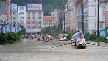 Local people paddle boats on a flooded street in Rongshui Yao Autonomous County, southwest China's Guangxi Zhuang Autonomous Region, on July 4, 2009. Floods caused by rainstorms since early the week have left four people missing and 11,845 others displaced in Guangxi.