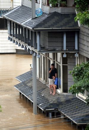 People wait for rescue on the platform of a building in the flood in Liuzhou, southwest China's Guangxi Zhuang Autonomous Region, on July 4, 2009. 