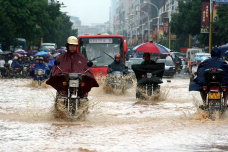 Vehicles wade through a flooded street in Nankang City, east China's Jiangxi Province, on July 4, 2009. Rainstorms have swept Jiangxi since Tuesday, leaving two people dead, one missing and over 3.9 million others affected.