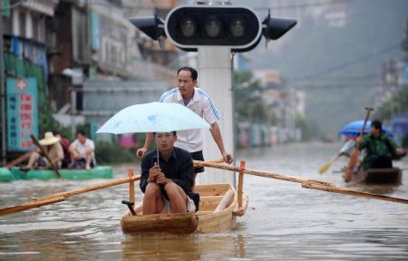 Local people paddle boats on a flooded street in Rongshui Yao Autonomous County, southwest China's Guangxi Zhuang Autonomous Region, on July 4, 2009.