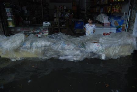 A girl watches a dam built with goods in front of a shop to resist the flood in downtown Yingtan City in south China's Jiangxi Province, on July 4, 2009. Heavy rain and storm struck the city saturday paralysing part of the city's communications.