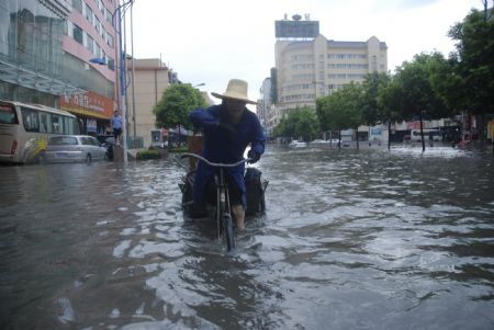 A local tricyclist struggles his way at the flooded street in downtown Yingtan City in south China's Jiangxi Province, on July 4, 2009. Heavy rain and storm struck the city saturday paralysing part of the city's communications.