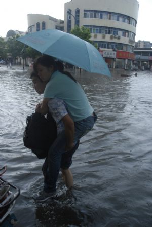 A local young couple manages their way in the flood in downtown Yingtan City in south China's Jiangxi Province, on July 4, 2009. Heavy rain and storm struck the city saturday paralysing part of the city's communications.