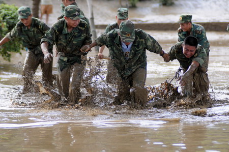 Soldiers try to clean away silt and rubbish left by floods that hit Liuzhou, southwest Guangxi Zhuang autonomous region on July 6,2009. [Xinhua]