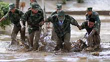 Soldiers try to clean away silt and rubbish left by floods that hit Liuzhou, southwest Guangxi Zhuang autonomous region on July 6,2009.