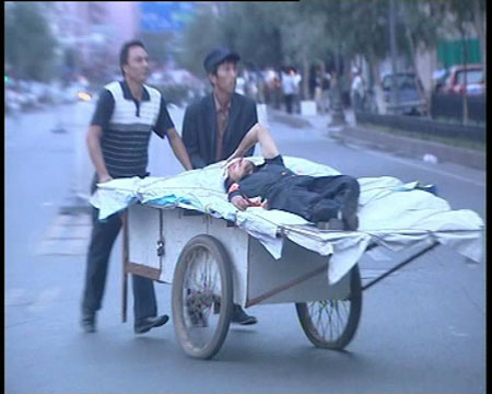 Photo released by police shows two citizens carrying a wounded person in Urumqi, capital of northwest China's Xinjiang Uygur Autonomous Region on July 5, 2009. [chinadaily.com.cn]