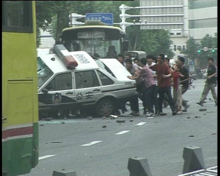 Photo released by police shows rioters smash and overturn a police car in Urumqi, capital of northwest China's Xinjiang Uygur Autonomous Region on July 5, 2009. [chinadaily.com.cn]