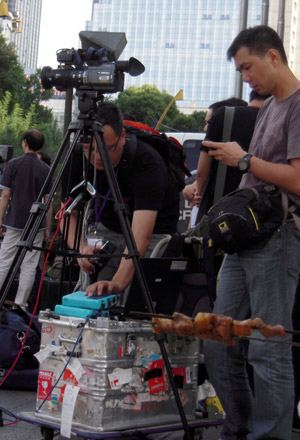 Reporters work outside a news center set up by local government in Urumqi, capital of northwest China's Xinjiang Uygur Autonomous Region, on July 8, 2009. 