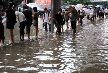 Citizens wait for bus on the flooded road in Nanjing, capital of east China's Jiangsu Province, on July 7, 2009. A heavy downpour drenched the city and blocked the traffic from Monday night to Tuesday morning.