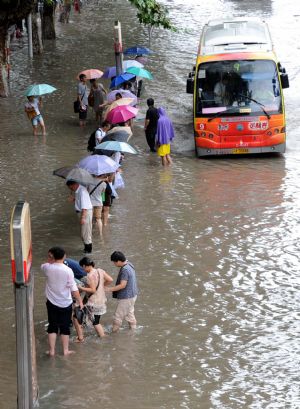 Citizens wade on the flooded road in Nanjing, capital of east China's Jiangsu Province, on July 7, 2009. A heavy downpour drenched the city and blocked the traffic from Monday night to Tuesday morning.