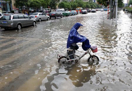 A citizen wade on the flooded road in Nanjing, capital of east China's Jiangsu Province, on July 7, 2009. A heavy downpour drenched the city and blocked the traffic from Monday night to Tuesday morning.