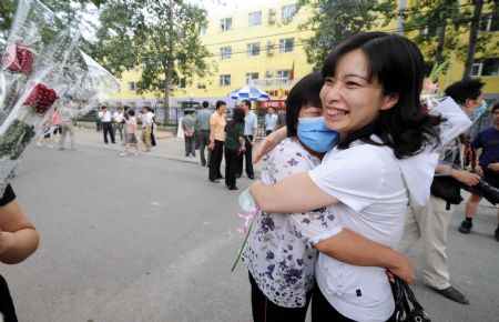 A teacher from Nanhu Zhongyuan Primary School (L) is greeted by her colleague after being quarantined due to influenza A/H1N1 concern for a week in Beijing, capital of China, on July 7, 2009. 