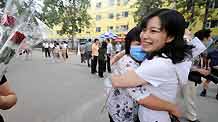 A teacher from Nanhu Zhongyuan Primary School (L) is greeted by her colleague after being quarantined due to influenza A/H1N1 concern for a week in Beijing, capital of China, on July 7, 2009.