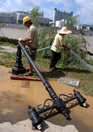 Two electricians repair the street lights destroyed during the flood along the Liujiang River in Liuzhou City of southwest China's Guangxi Zhuang Autonomous Region, on July 7, 2009. The flood passing through Liujiang River receded on July 6 and local people began to clean the city and restore the basic facilities.