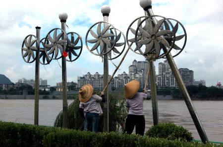 Two street cleaners clean the city sculptures along the Liujiang River after the flood receded in Liuzhou City of southwest China's Guangxi Zhuang Autonomous Region, on July 7, 2009. The flood passing through Liujiang River receded on July 6 and local people began to clean the city and restore the basic facilities. 